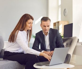 man and woman working together in front of computer to create an email newsletter