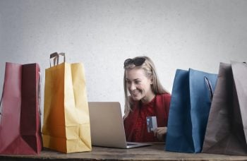 woman surrounded by shopping bags holding credit card